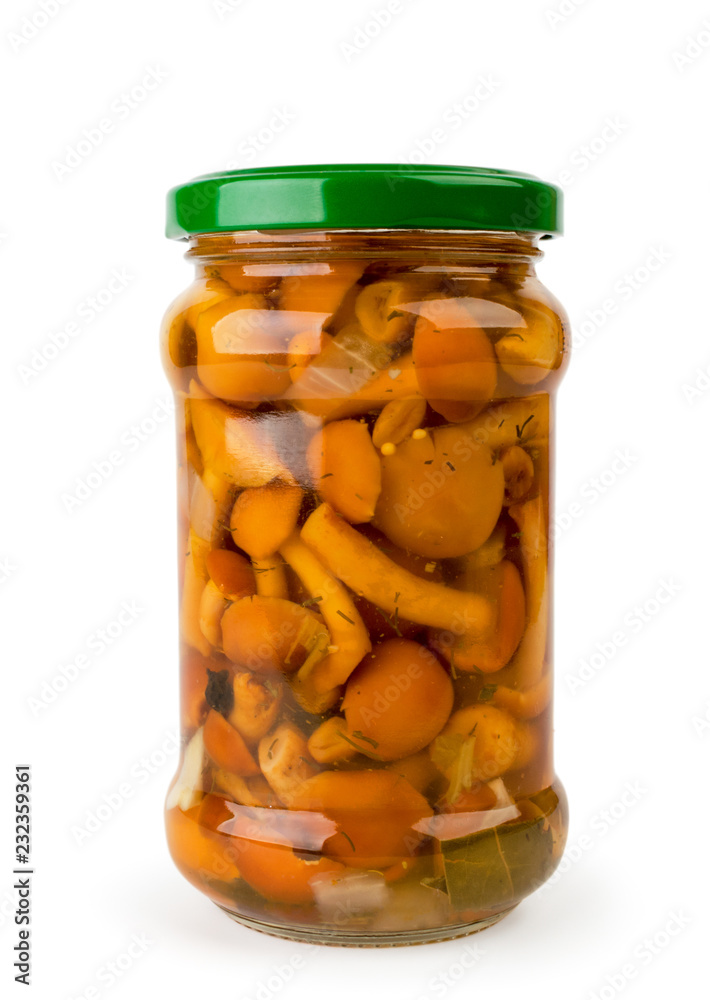 Marinated mushrooms in a glass jar close-up on a white. Isolated Marinated mushrooms in a glass jar close-up on a white. Isolated