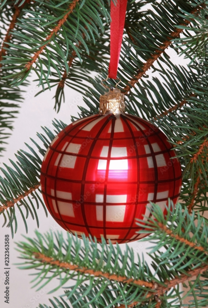 red checkered christmas ball on a spruce tree red checkered christmas ball on a spruce tree