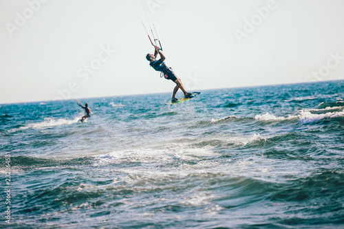 Professional kiter makes the difficult trick on a beautiful background. Kitesurfing Kiteboarding action photos man among waves quickly goes