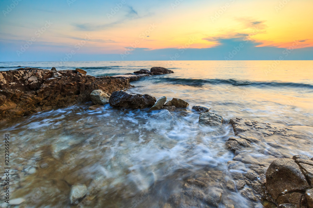 Enjoying the colorful sunset on a beach with rocks on the Adriatic Sea coast Istria Croatia