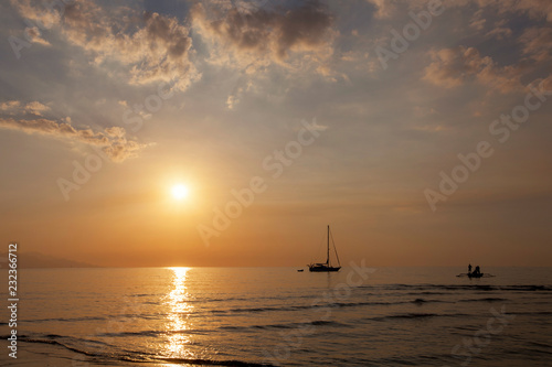Beautiful dusk on the beach and silhouette of fishing boat and sailing boat