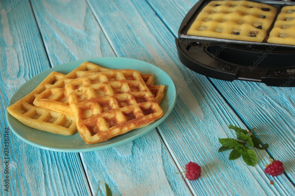 Baking cookies in an electric waffle iron, on a wooden surface. Baking cookies in an electric waffle iron, on a wooden surface.