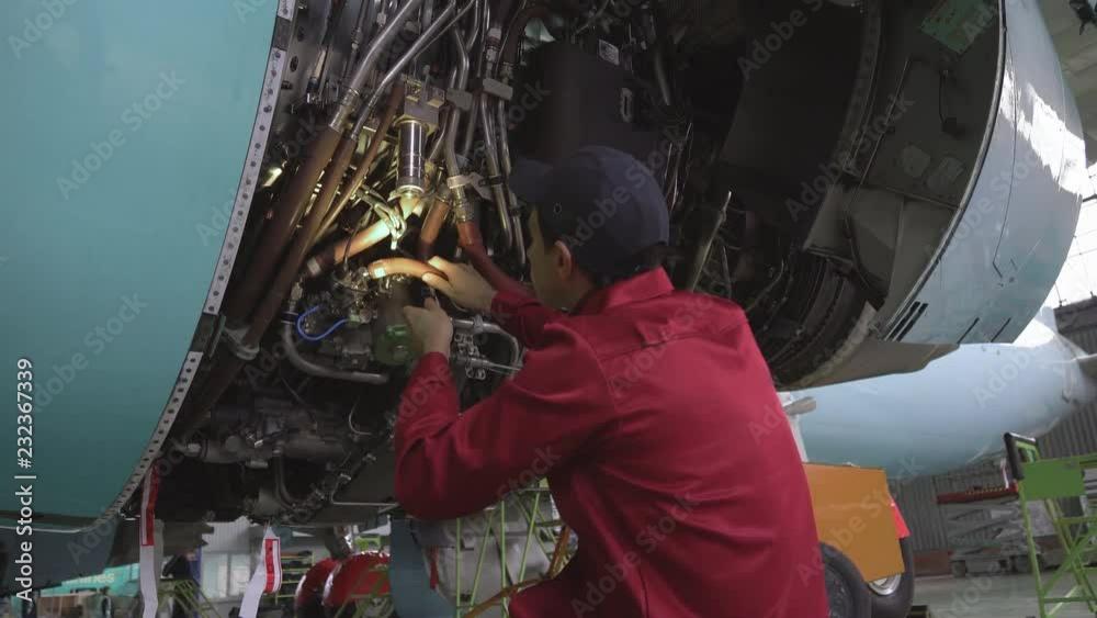 Engineer, technician examines the jet engine with a flashlight. The