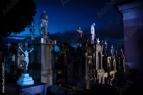 Jesus statues at dark blue lightened tombstones during dawn in Cementerio General in Merida, Mexico photo