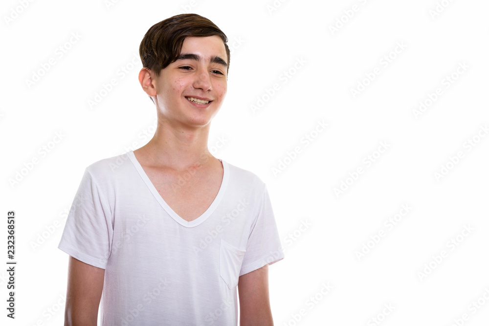 Studio shot of young happy Persian teenage boy smiling while loo Studio shot of young happy Persian teenage boy smiling while loo