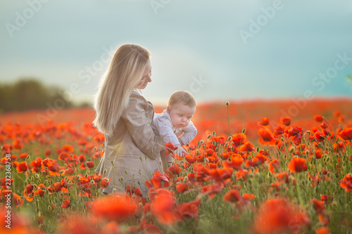 Happy motherhood. Mom and son daughter are playing in the field of flowering red poppies