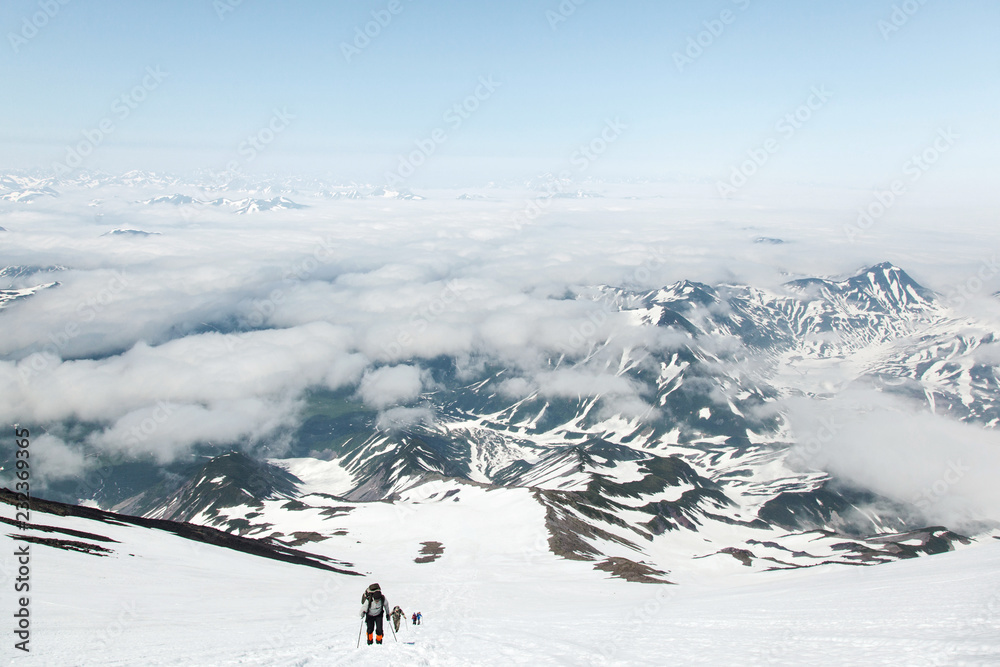 Climbing tourists in the mountains. Snow rocks and clouds in Kamchatka.