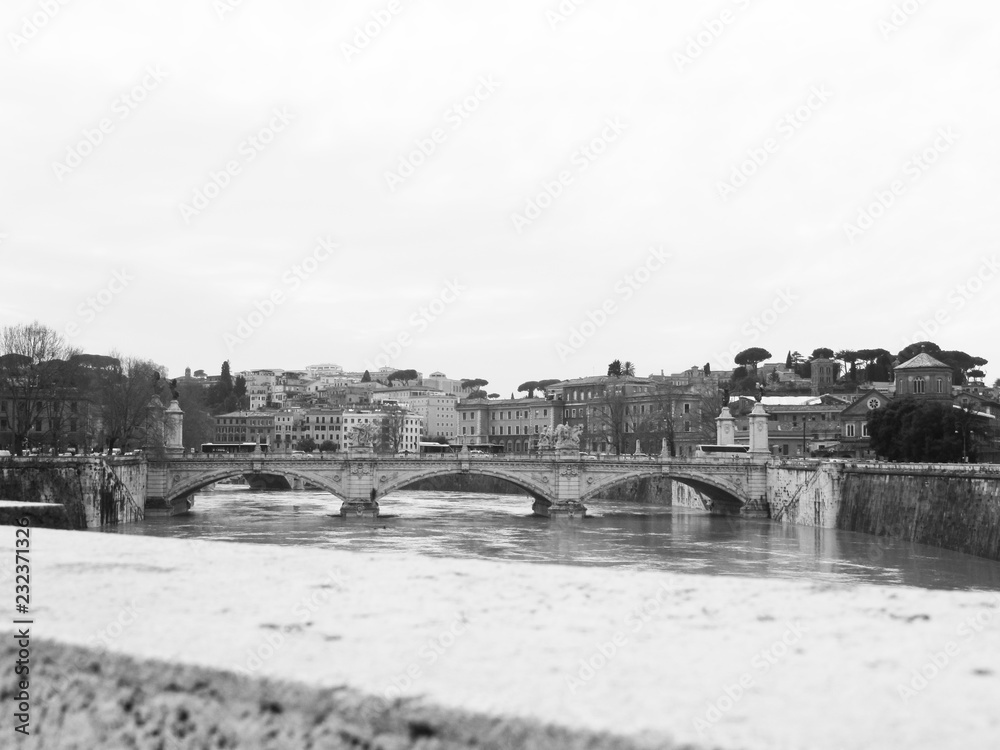 View of a beautiful Rome district and the river from a stone bridge on a rainy day. Black and white. Italy