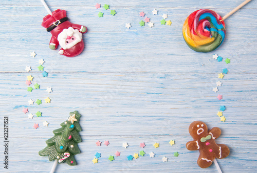 Sweet candies on a stick in shapes of Christmas tree, Gingerbread man and Santa Claus, Christmas frame on a wooden background