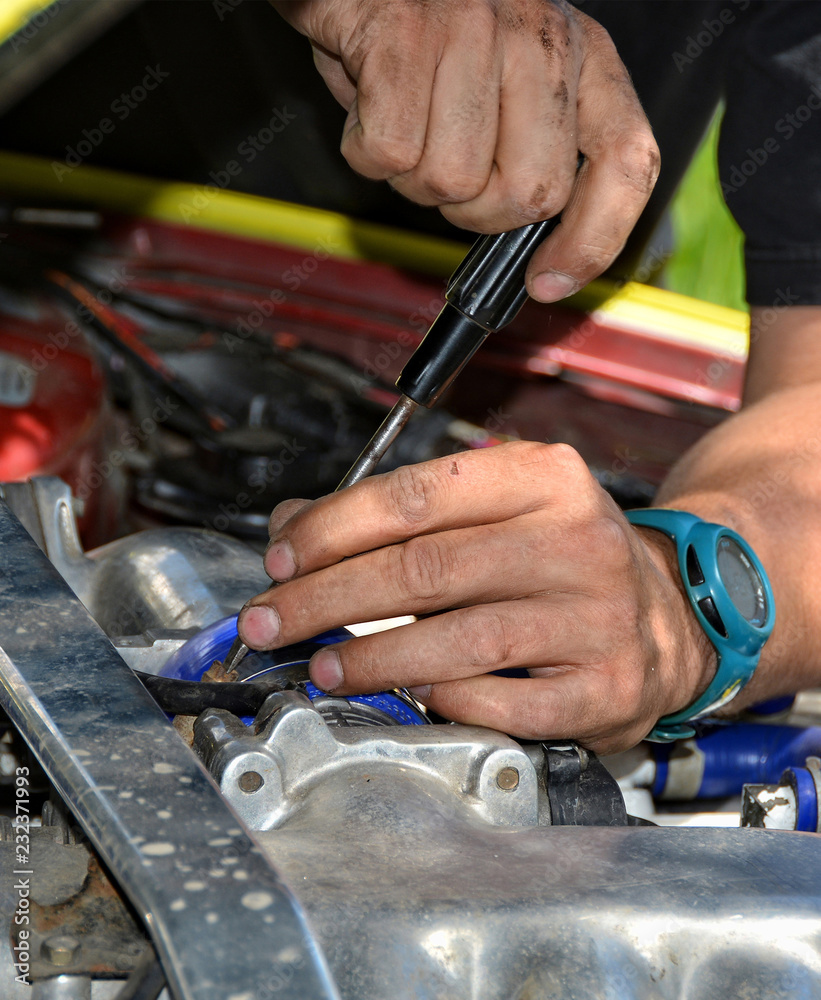 Man at work in a garage. Auto mechanic worker in car repair service. Detail image of mechanic hands with tool. Auto repair concept. Close up.