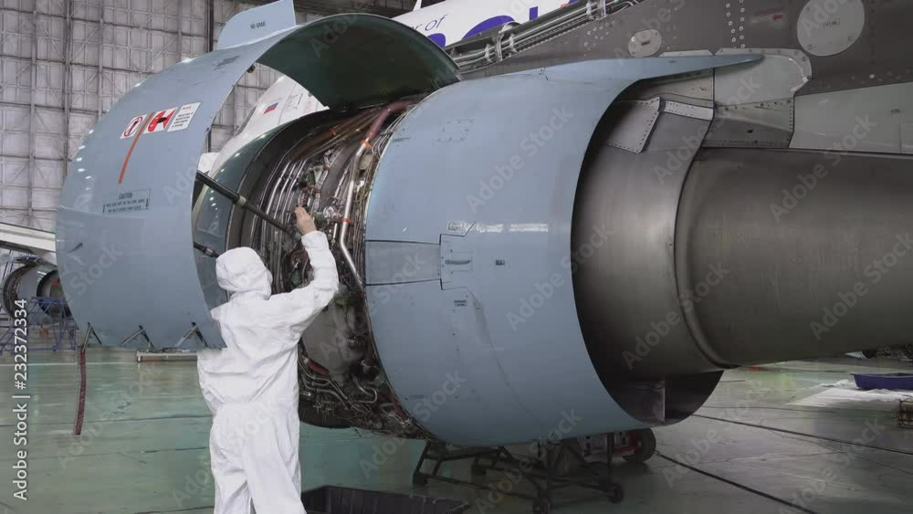 Engineer, technician examines the jet engine with a flashlight. The repair of aircraft in the hangar. Maintenance of aircraft. 4k