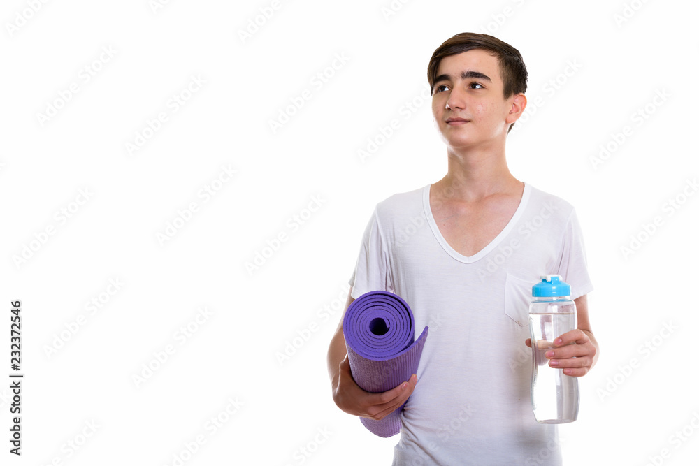 Studio shot of young handsome Persian teenage boy thinking while Studio shot of young handsome Persian teenage boy thinking while
