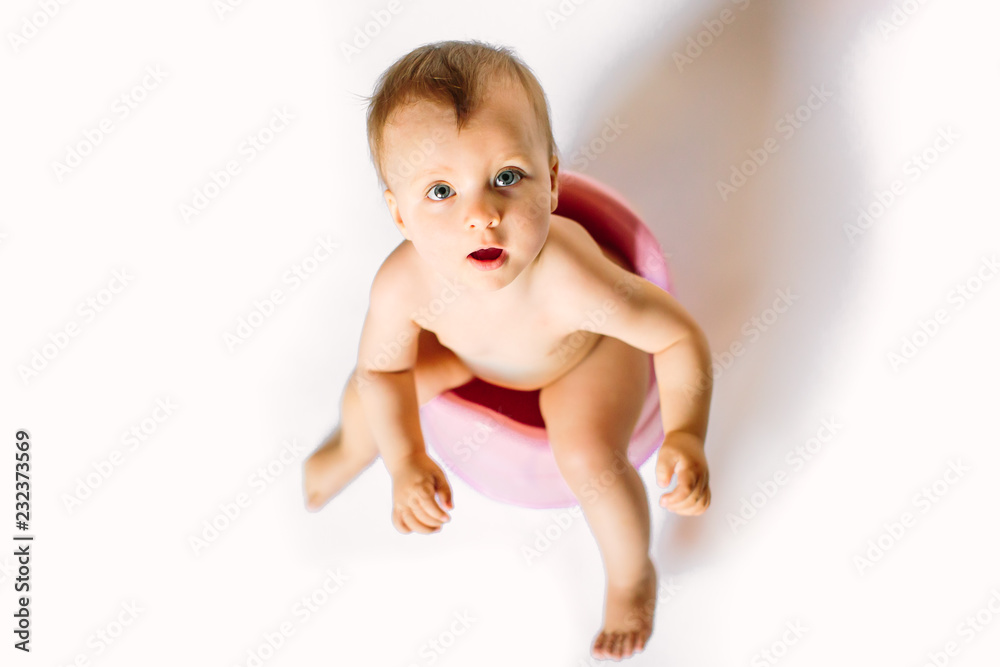 Cute little girl at home is sitting on the chamber pot , concept of potty training for kids, selective focus photograph Cute little girl at home is sitting on the chamber pot , concept of potty training for kids, selective focus photograph