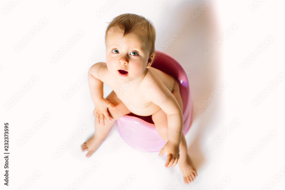 baby girl sits on a children's pot, toilet on a white background baby girl sits on a children's pot, toilet on a white background