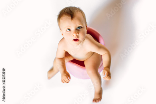 Cute little girl at home is sitting on the chamber pot , concept of potty training for kids, selective focus photograph