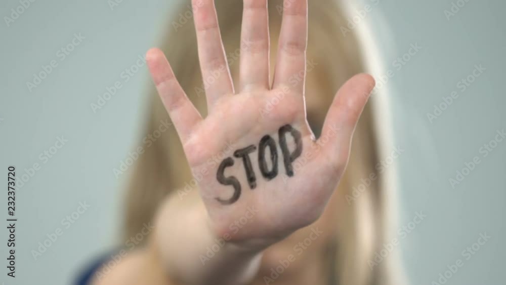 Scared young girl showing stop sign, domestic violence victim, abuse awareness