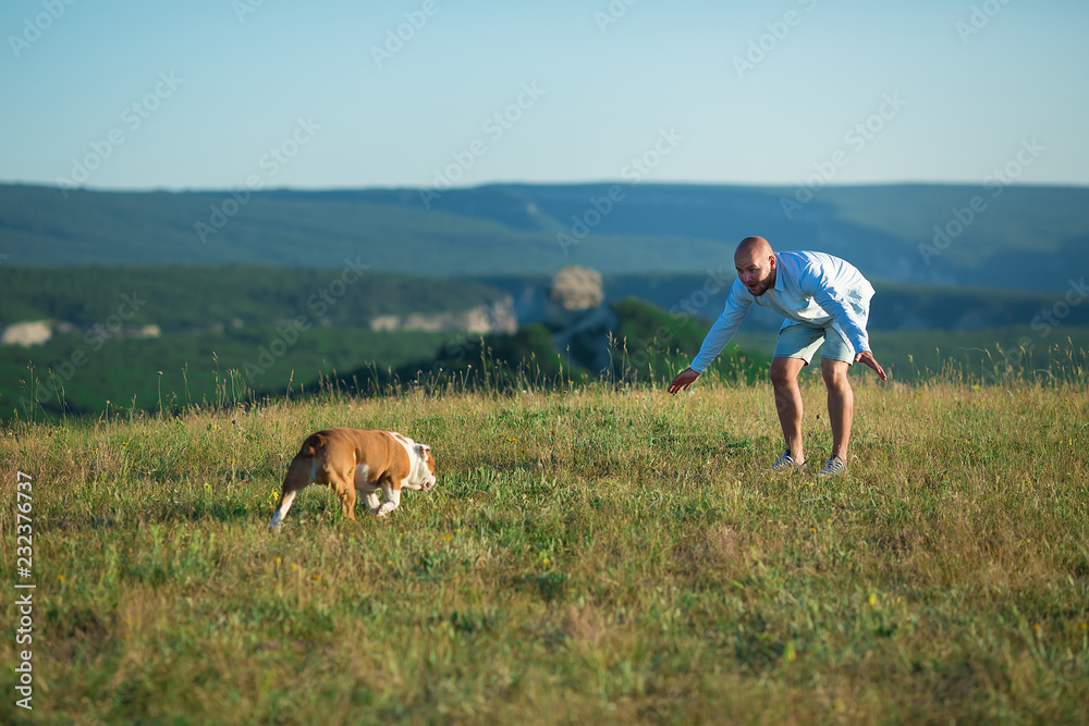 Man handsome walking with his english bull dog in mountains dressed in cozy jeans blue shorts