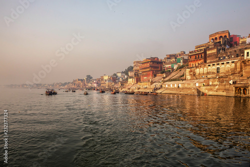 aranasi Ganges river ghat with ancient architectural buildings and temples as viewed from a boat on the river at sunset © Tjeerd