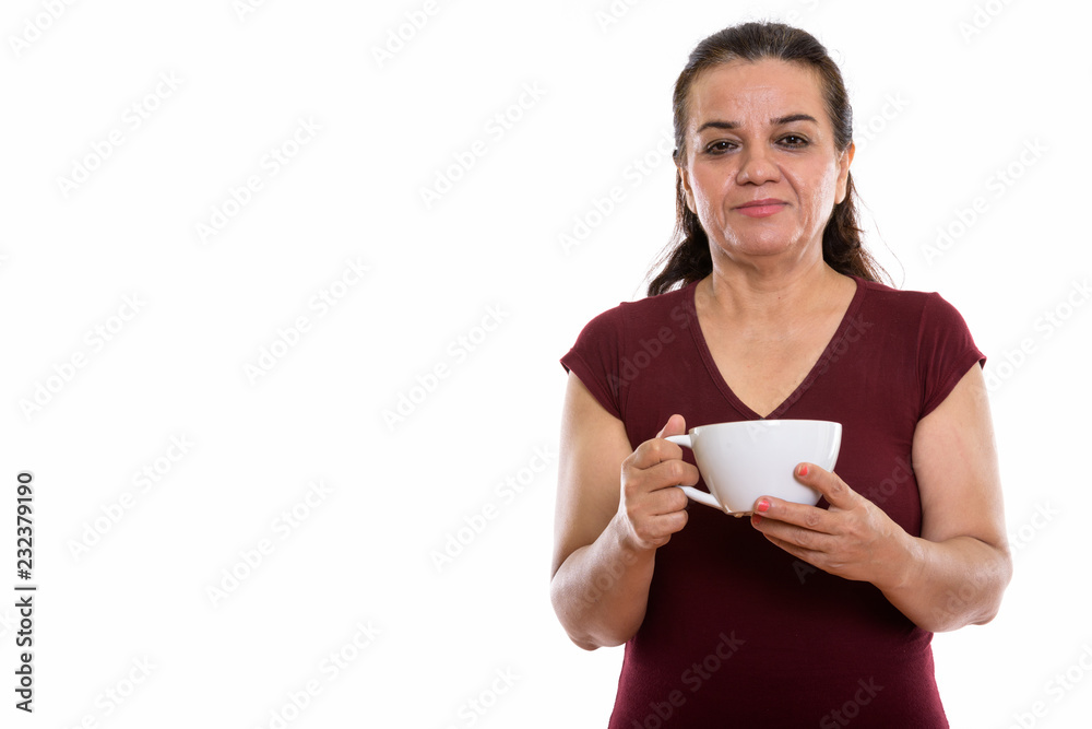 Studio shot of mature Persian woman holding coffee cup Studio shot of mature Persian woman holding coffee cup
