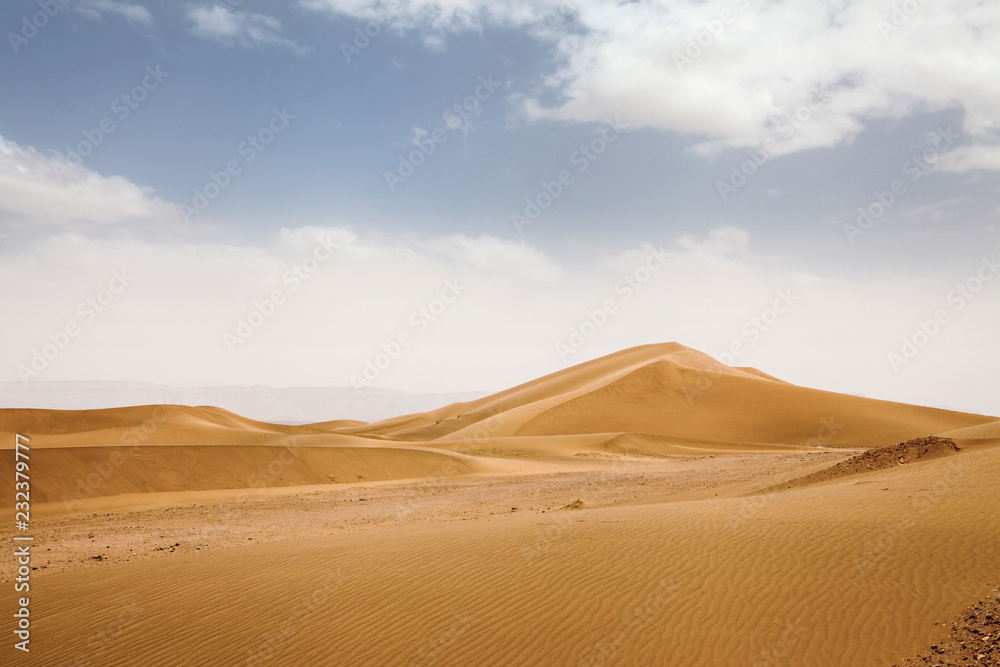 Desert Landscape of zagora in Marocco, with a blue sky, stones, bushes and clouds