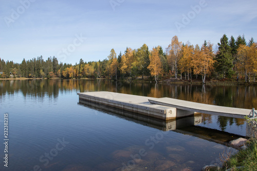 Lake-side decking with autumnal forest reflections