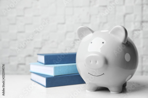 Piggy bank with stack of books on table