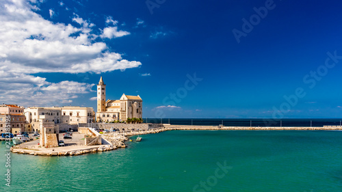 The beautiful Romanesque Cathedral Basilica of San Nicola Pellegrino, in Trani. Construction in limestone tuff stone, pink and white. A pointed arch under the bell tower. Italy, Puglia, Bari, Barletta photo