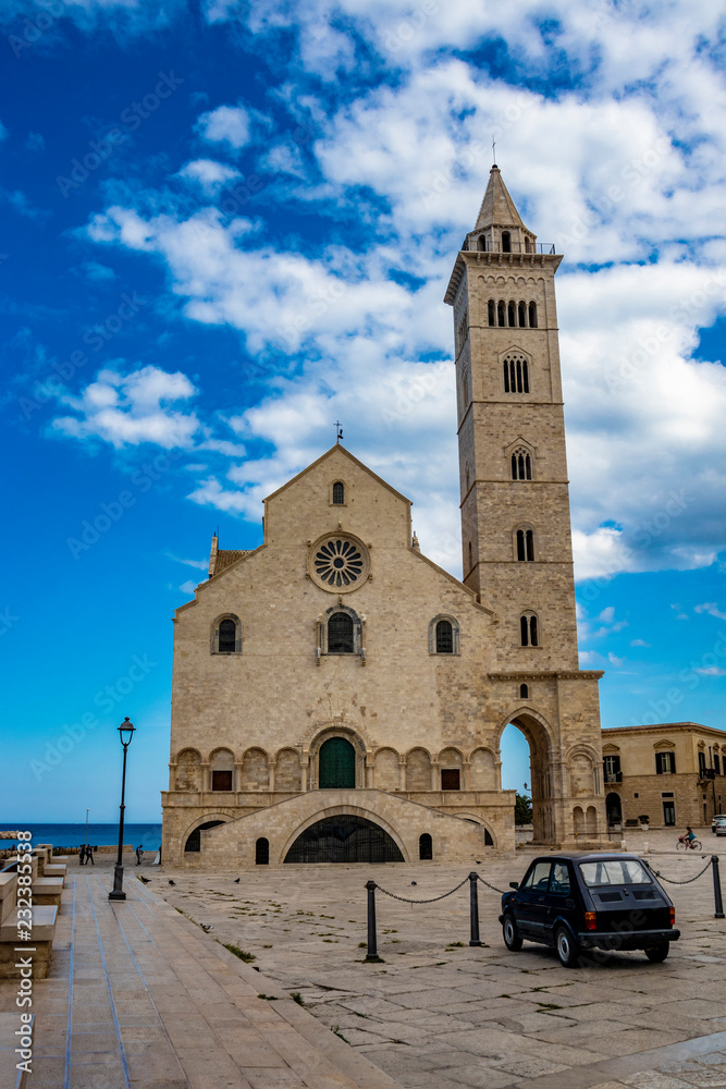 The beautiful Romanesque Cathedral Basilica of San Nicola Pellegrino, in Trani. Construction in limestone tuff stone, pink and white. vintage car parked. In Puglia, near Bari, Barletta, Andria, Italy.