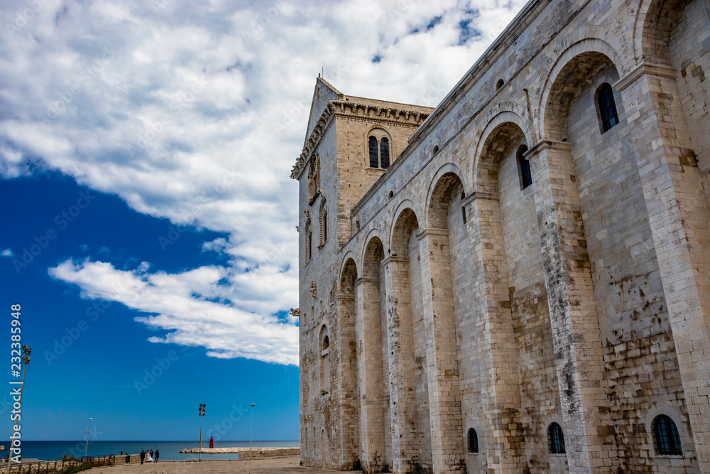 The beautiful Romanesque Cathedral Basilica of San Nicola Pellegrino, in Trani. Construction in limestone tuff stone, pink and white. A pointed arch under the bell tower. Italy, Puglia, Bari, Barletta