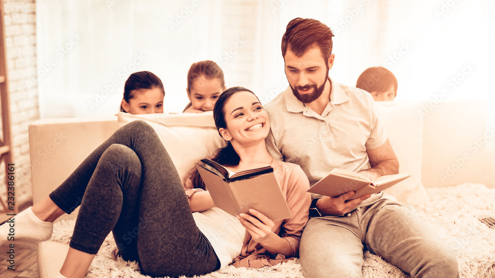 Young Cute Parents Reading Book while Kids Playing