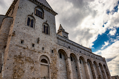 The beautiful Romanesque Cathedral Basilica of San Nicola Pellegrino  in Trani. Construction in limestone tuff stone  pink and white. A pointed arch under the bell tower. Italy  Puglia  Bari  Barletta