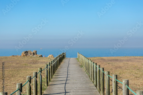 Perspective view of wooden pedestrian walkway  towards the ocean  next to the beach