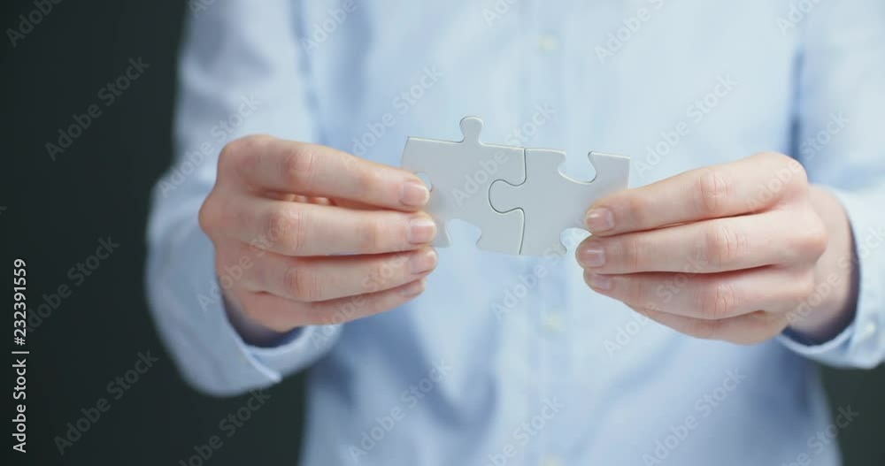 Woman joining two white puzzle pieces together. Woman joining two white puzzle pieces together.
