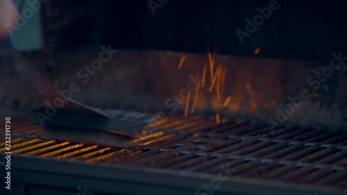 Man Cleaning off Grill Grate By Scraping off the Old Excess Food