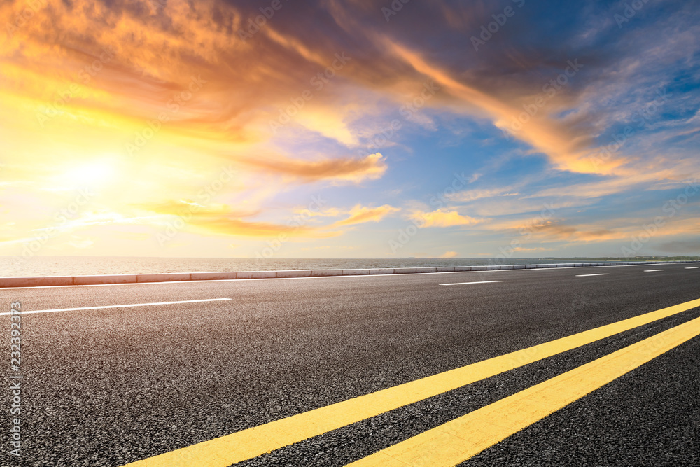Asphalt road and dramatic sky with coastline at sunset Asphalt road and dramatic sky with coastline at sunset