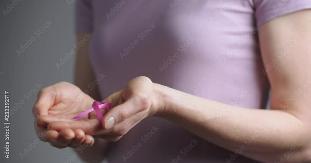 A casual young woman holding a pink ribbon in her hands. A casual young woman holding a pink ribbon in her hands.