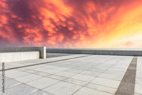 Empty square floor and dramatic sky with coastline at sunset