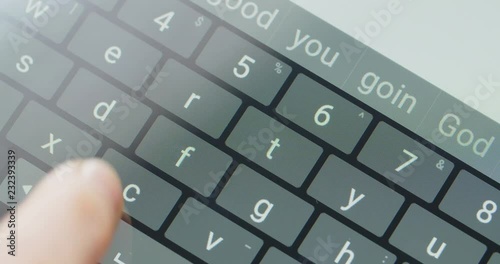 Female hand typing on touchscreen, with word suggestions. Closeup top view shot.
