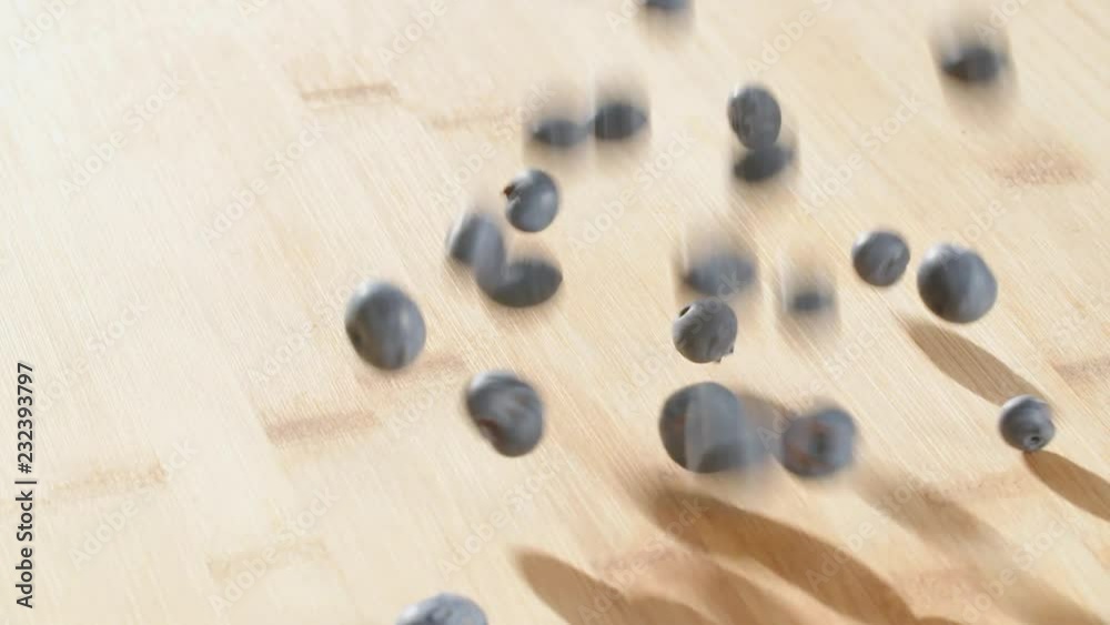 Slow motion shot of blueberries falling on a wooden surface. Slow motion shot of blueberries falling on a wooden surface.