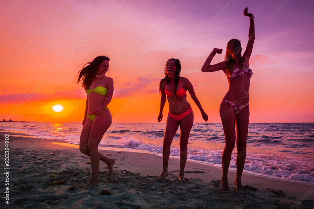 Fototapeta premium tres chicas disfrutando y riendo al atardecer en una playa paradisiaca.