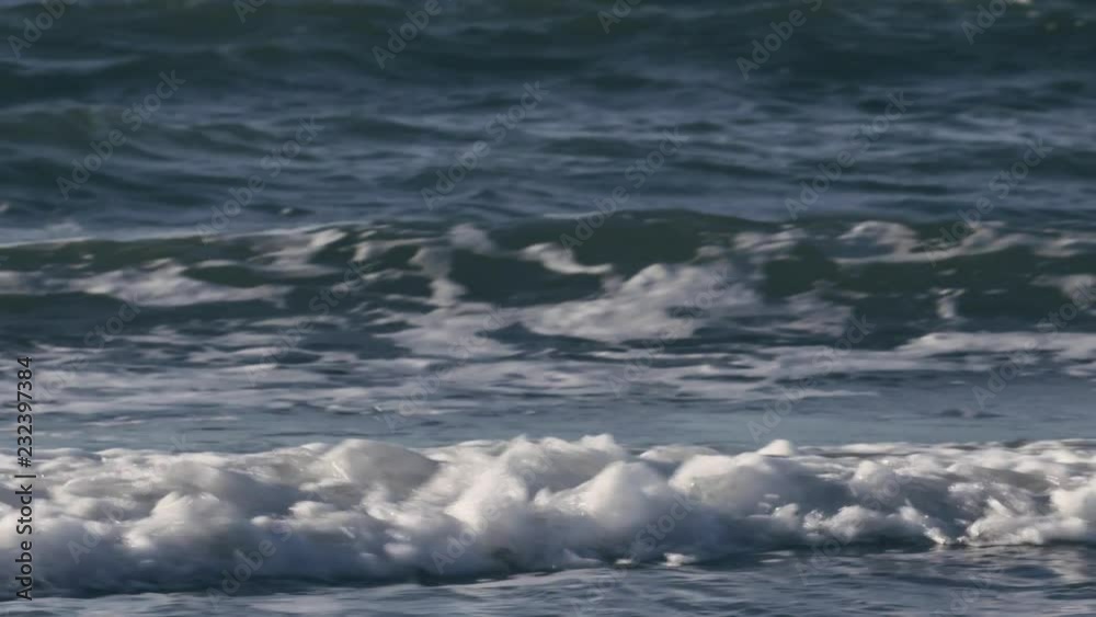 Slow motion panning shot of ocean waves hitting a beach on a sunny summer day. Hoek van Holland, The Netherlands. Slow motion panning shot of ocean waves hitting a beach on a sunny summer day. Hoek van Holland, The Netherlands.