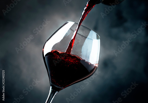 French dry red wine, pours into glass, gray background, selective focus photo