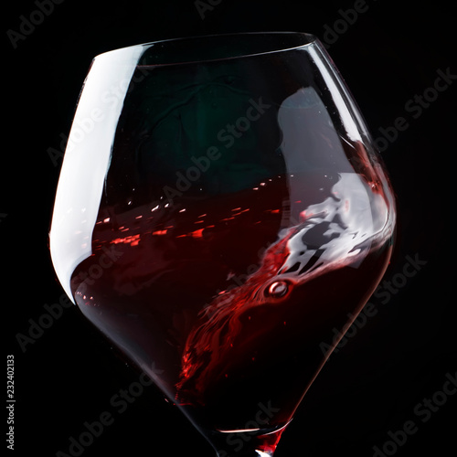 Red wine, splash in a glass, dry cabernet sauvignon, dark background, defocused in motion image, shallow depth of field photo