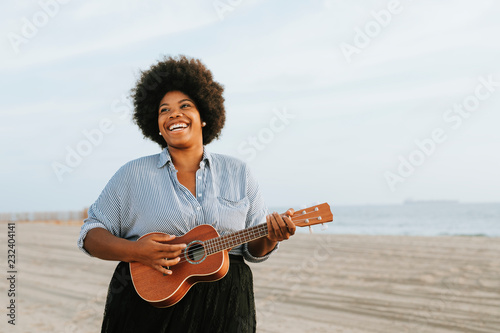 African American musician playing ukulele at the beach photo