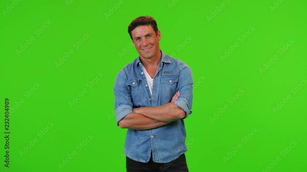 Cute young man poses for the camera, smiling and looking into the lens over a green screen Cute young man poses for the camera, smiling and looking into the lens over a green screen