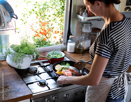 Woman cooking salmon in a pan