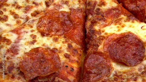 Sliced whole pepperoni pizza spinning video close up