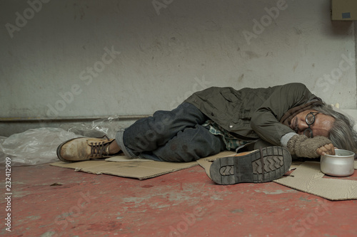 Older homeless dirty poor beggar man sleeping and waiting to help from donor. He so hungry, unhappy, have not money and feel lonely. photo