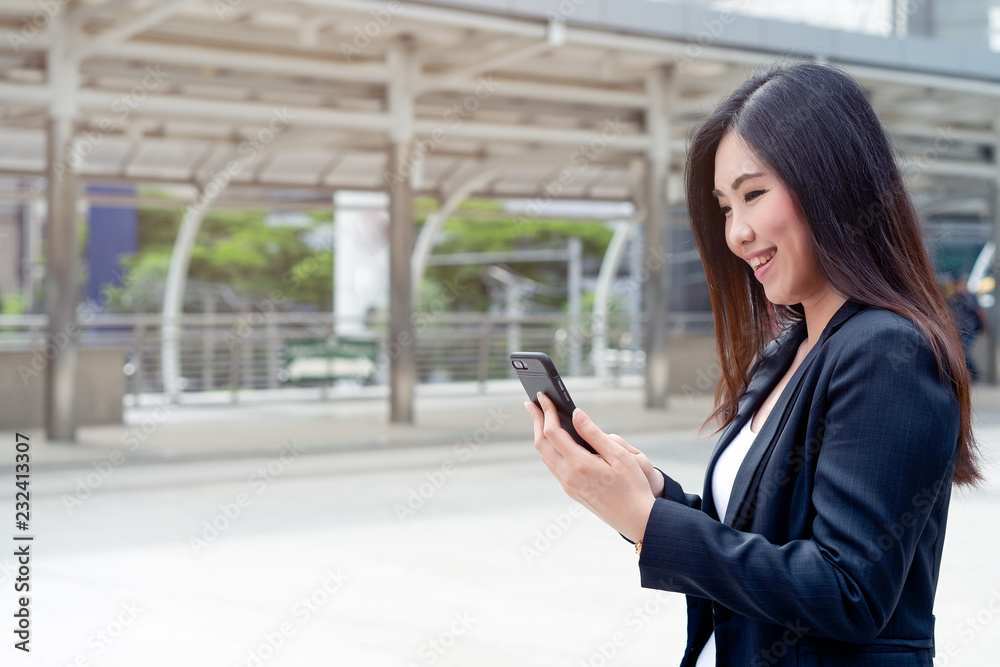Asian attractive beautiful business woman using her smartphone for ark her subordinate about progress of professional project at outside the office. Business Outdoor Concept.