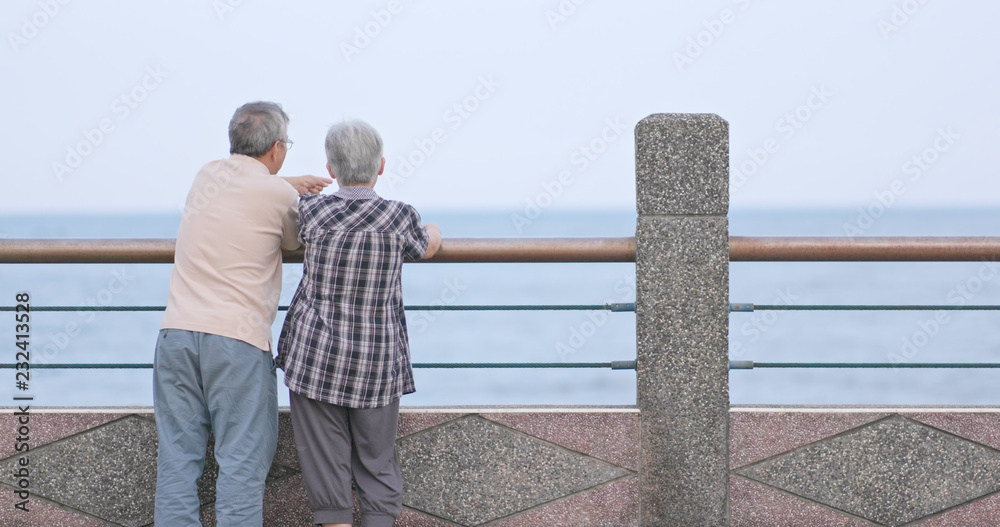 Old couple chatting and looking at the sea together Old couple chatting and looking at the sea together
